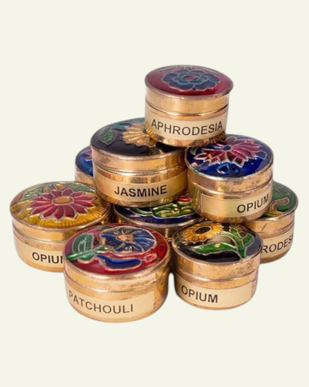 ULA assorted natural creme perfumes in decorative gold tins with floral designs and scent names like Opium, Jasmine, and Patchouli.